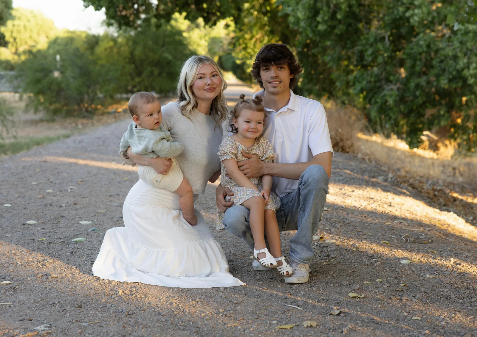 Ryun Brewer with his wife and their two young children on a tree-lined dirt lane in Arizona.